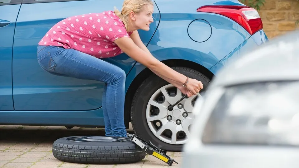 29 Apr 2014 --- Woman Changing Flat Tyre On Car --- Image by © Ian Lishman/Juice Images/Corbis